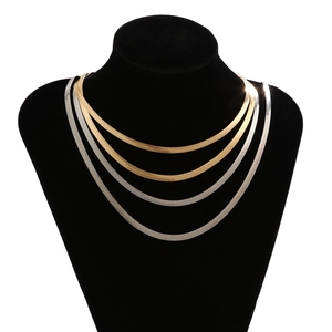 Close-up of layered gold and silver flat snake bone necklaces on a black neck bust