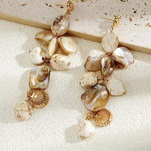Detail of bohemian gold shell earrings with natural pearls and starfish charms