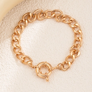 Chunky gold chain bracelet with spring ring clasp on textured stone background