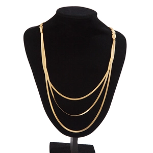 Detailed view of layered gold flat snake bone chain necklace on a black display stand