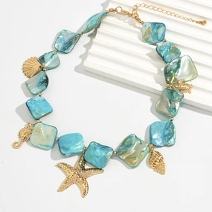Detail of turquoise shell beads with gold starfish and seahorse pendants on necklace