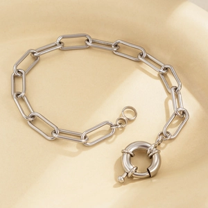 Detail of silver paperclip chain bracelet with oversized sailor clasp on ceramic tray