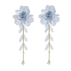 Détail de boucles d'oreilles fleurs bleu clair à plusieurs niveaux avec barres d'or