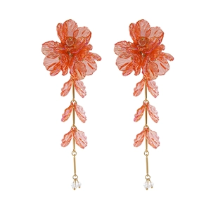 Détail de boucles d'oreilles fleuries avec pétales orange-rose et petites perles blanches