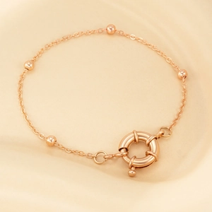 Detail shot of rose gold bead bracelet featuring a large oversized spring ring clasp