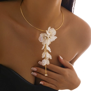 Gros plan d'un collier choker doré orné d'un grand pendentif fleur blanche en cascade