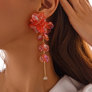 Détail des boucles d'oreilles fleurs orange irisées avec finition dorée de luxe