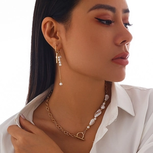 Détail d'un collier asymétrique avec chaîne dorée et perles baroques sur un mannequin