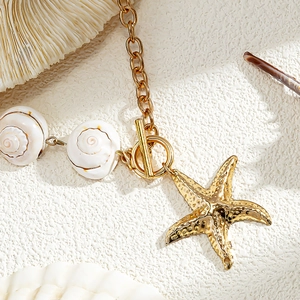 Detailed close-up of a gold starfish pendant necklace with shells and T-bar clasp