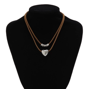 Detail van dubbellaagse ketting met zilveren kralen en hart hanger op bruin koord
