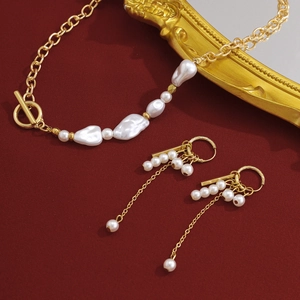 Détail de parure collier chaîne dorée avec perles et boucles d'oreilles assorties