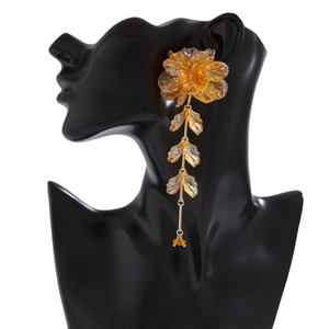 Détail de boucles d'oreilles fleur ambre avec pampilles de feuilles en résine étagées