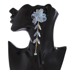 Vue détaillée de longues boucles d'oreilles fleur bleue avec chaînes dorées et feuilles