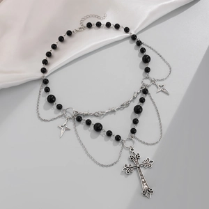 Dettaglio del ciondolo a croce gotica e stella su collana di perle a strati