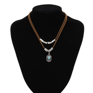 Detail van boheemse gelaagde bruine suède ketting met turquoise hanger op display