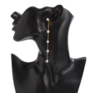 Détails de boucles d'oreilles pendantes dorées avec cinq perles blanches sur modèle