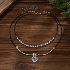 Dubbellaagse kralenketting met zilveren buisje en ronde reliëf munt hanger details