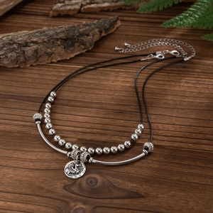 Detail van een dubbellaagse ketting met Pegasus munt hanger en zwarte koord
