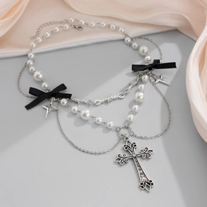 Dettaglio di collana gotica multistrato con perle, fiocchi neri e pendente a croce