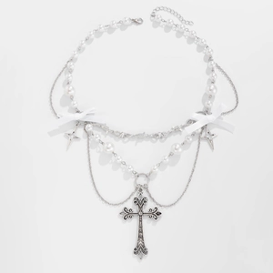 Dettaglio macro della collana di perle a strati con croce d'argento vintage e fiocchi