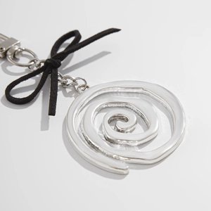 Gros plan du porte-clés avec pendentif en spirale argentée et décor de nœud en velours noir