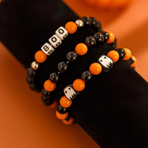 Detail von Halloween-Armbändern in Orange und Schwarz mit BOO-Anhängern und Geistern