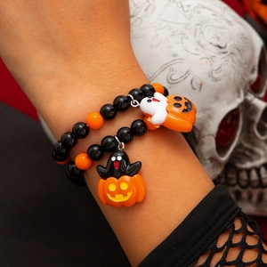 Detail eines Halloween-Perlenarmbands mit Geist- und Kürbisanhängern am Handgelenk eines Modells