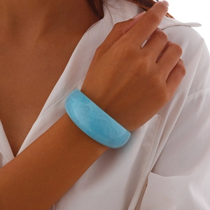 Macro detail of wide translucent light blue acrylic bangle with marble texture on wrist