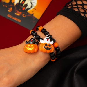 Nahaufnahme von Halloween-Perlenarmbändern mit Kürbis- und Geist-Anhängern am Modell