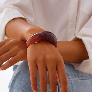 Macro shot of an amber resin cuff bracelet with polished texture on a woman arm
