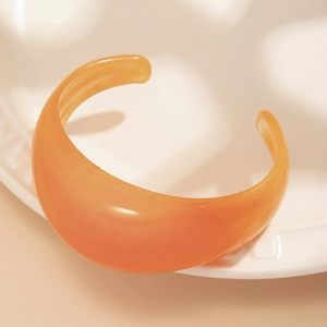 Detail view of amber orange translucent acrylic cuff bracelet with smooth curved texture