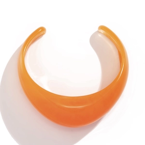 Detailed view of the orange acrylic resin bangle with a polished smooth curved surface