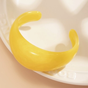 Close-up of bright yellow resin cuff bracelet with marble texture on ceramic plate