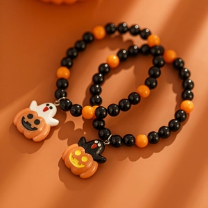 Makroaufnahme von Halloween-Kürbis- und Geist-Anhängern an schwarz-orangen Perlenarmbändern