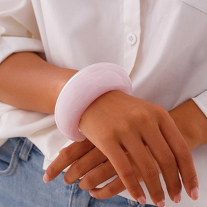 Close-up of a wide pink translucent acrylic cuff bracelet worn with a casual outfit