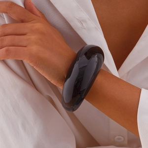 Close-up of minimalist chunky black resin bangle bracelet with a glossy finish