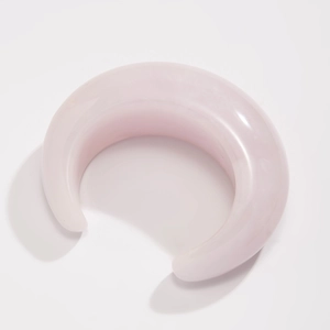 Detail of pink acrylic resin crescent bangle with smooth translucent texture
