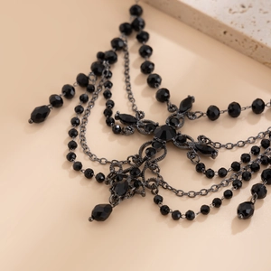 Macro detail of gothic beaded choker featuring black crystal droplets and tassel chains