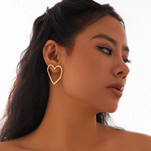 Nahaufnahme eines Models mit goldenen hohlen Herzohrringen in Lava-Struktur-Design