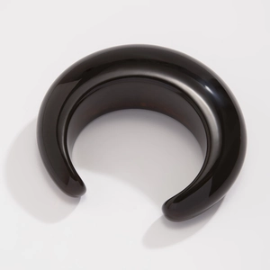 Close-up of a wide glossy black resin cuff bangle with smooth curved surface texture