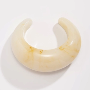 Macro detail of ivory acetate cuff bracelet with amber marble texture and glossy finish