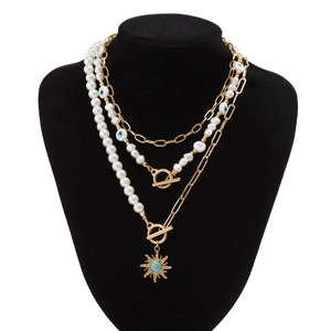 Nahaufnahme der mehrlagigen Boho-Goldkette mit Sonnenanhänger und Evil-Eye-Perlen