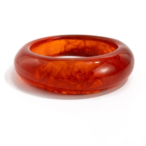 Detail of red translucent resin bangle featuring amber-like marbled texture and smooth finish