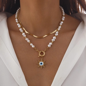 Detail einer Gold-Schlangenkette und Barockperlenkette mit Evil Eye Sonnenanhänger