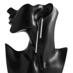 Detail view of long silver snake chain earrings on a mannequin showing drape and texture