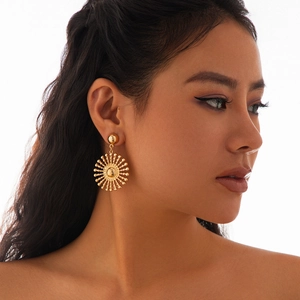 Nahaufnahme eines goldenen Sonnenblumen-Ohrrings, getragen von einem Modell auf Weiß