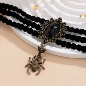 Detalle de gargantilla gótica con gema negra, marco de rosa en bronce y colgante de araña