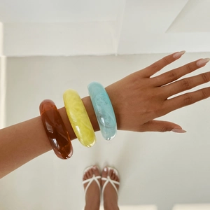 Macro shot of stylish resin bangles in dark brown, yellow, and light blue textures