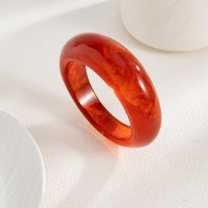 Macro shot of orange acetate resin bracelet with a natural marbled texture on white background