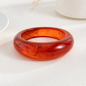 Close-up of thick amber acrylic bangle with natural smoke texture and polished finish